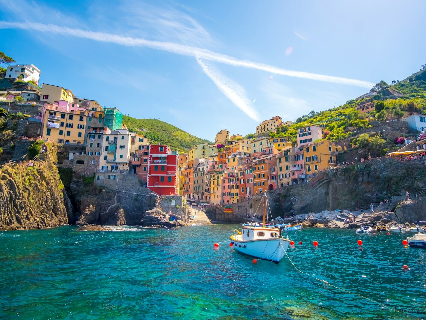blue fishing vessel near houses on mountain