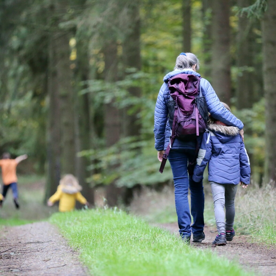 woman in blue denim jeans and black jacket walking with woman in green jacket