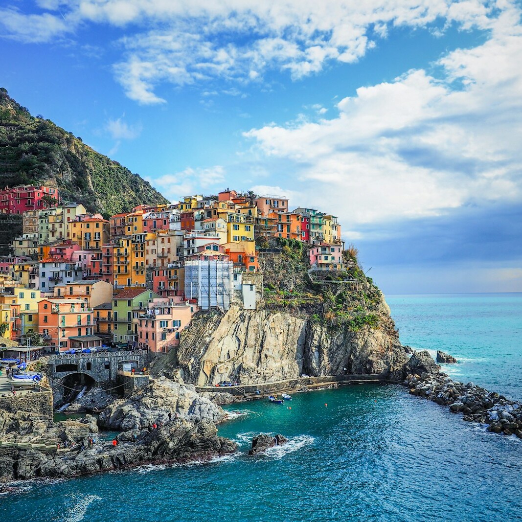 houses on mountain beside sea under blue sky during daytime