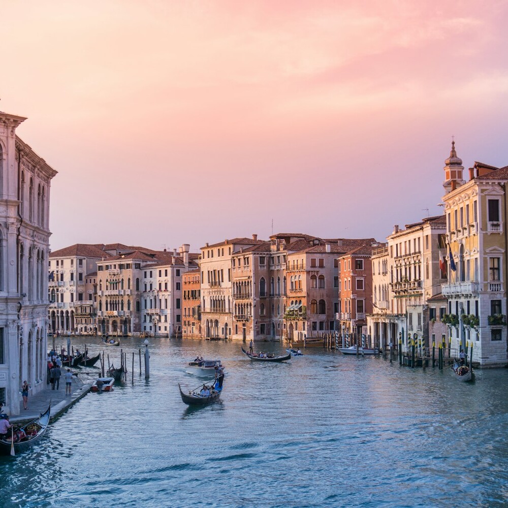 photo of gondolas on body of water between buildings