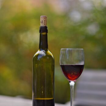 wine bottle beside wine glass on brown wooden surface