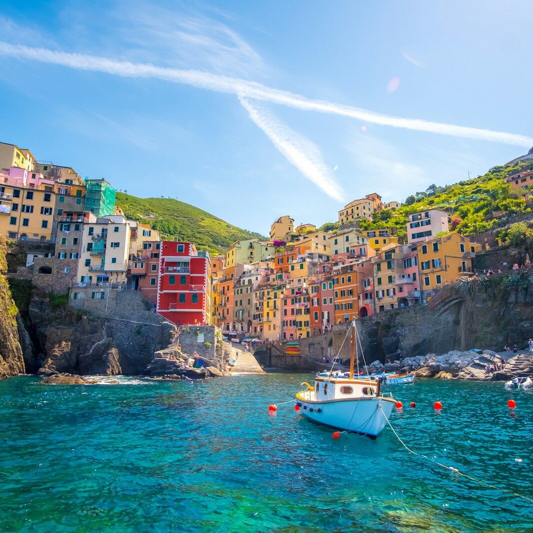 blue fishing vessel near houses on mountain
