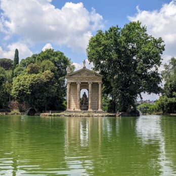 a lake with a gazebo surrounded by trees
